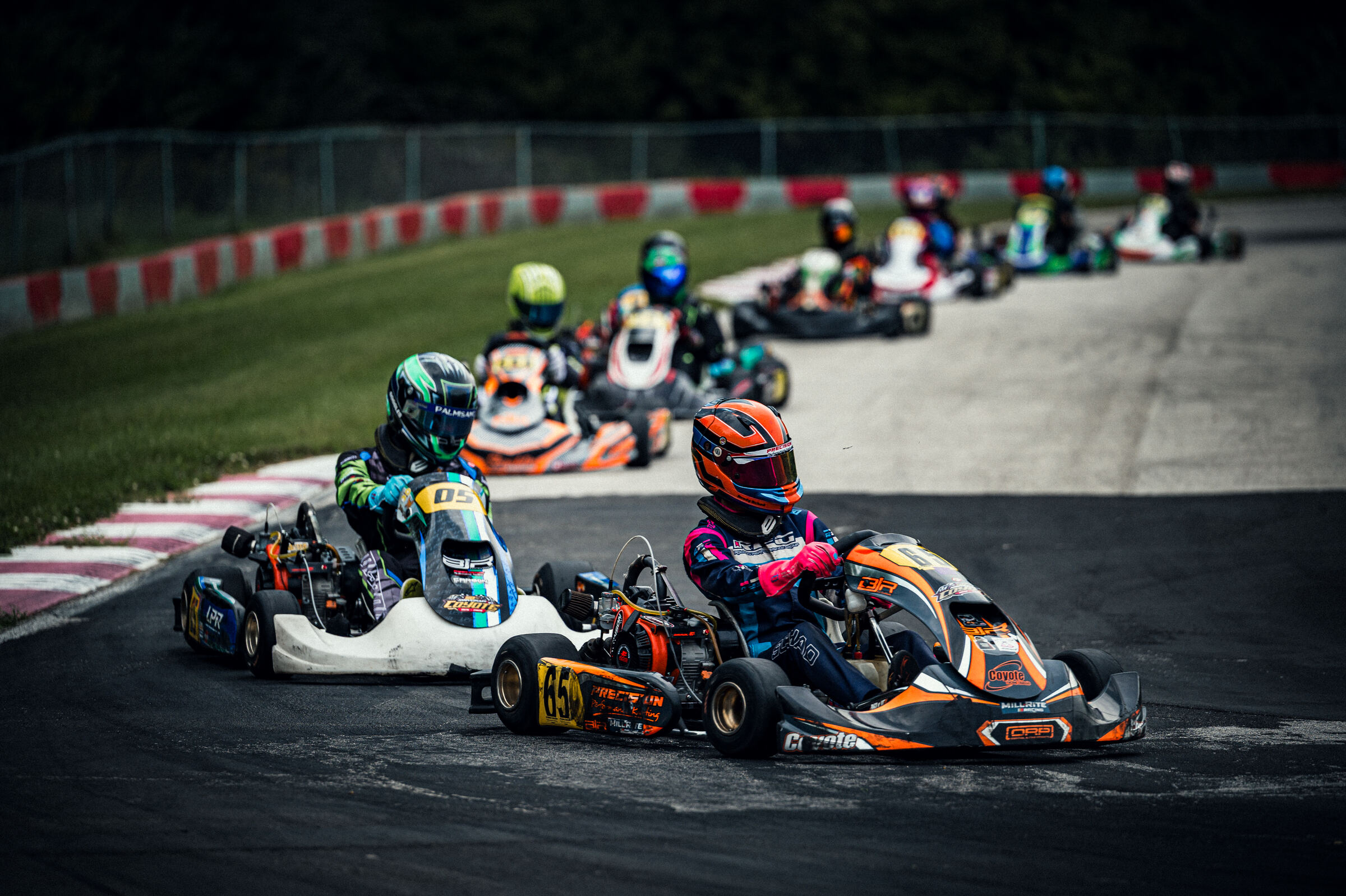 Brady Schad leading a pack through a corner in the orange and blue Mill-Rite Racing kart